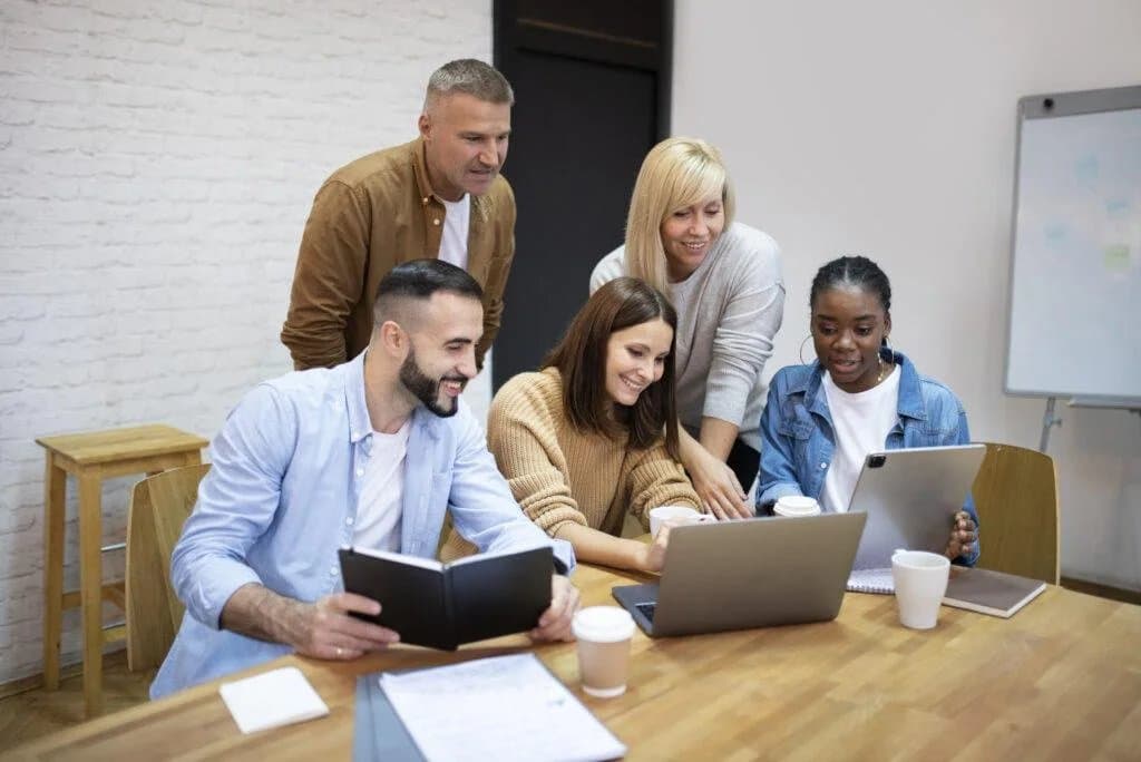 A diverse team reviewing hiring and growth plans together on a laptop