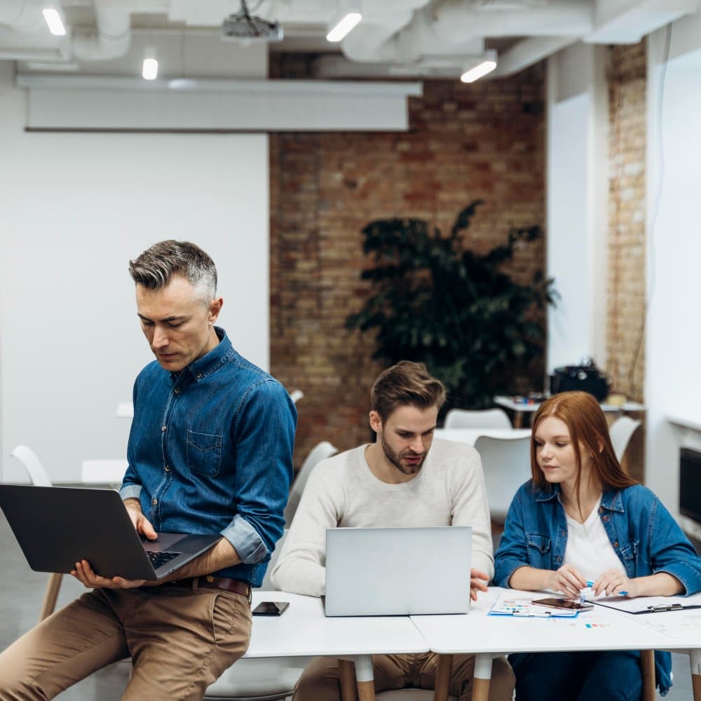 Three colleagues working together on laptops in a modern office